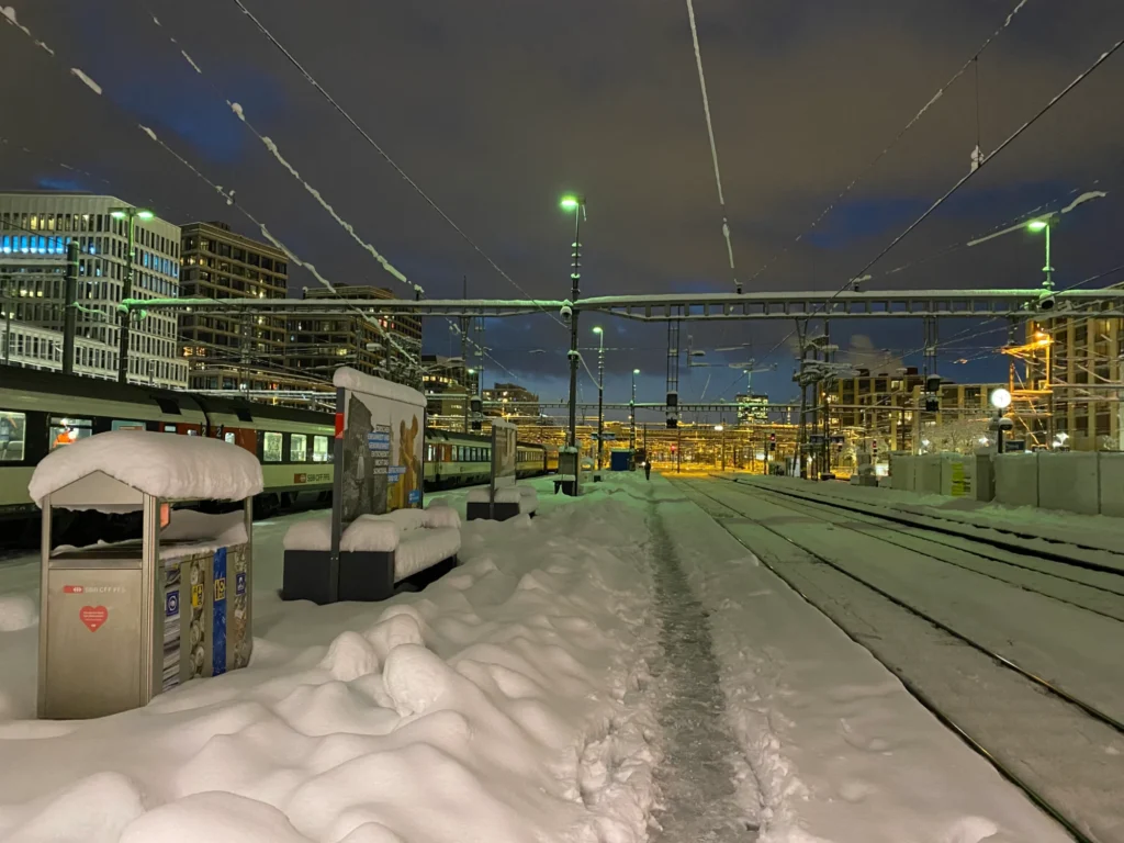 Snow-covered platforms at Zurich main station in the evening with trains under the lights