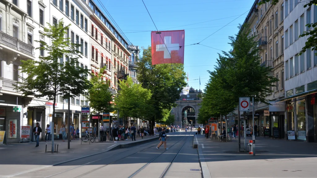 Bahnhofstrasse in Zurich with tram tracks, trees and a Swiss flag